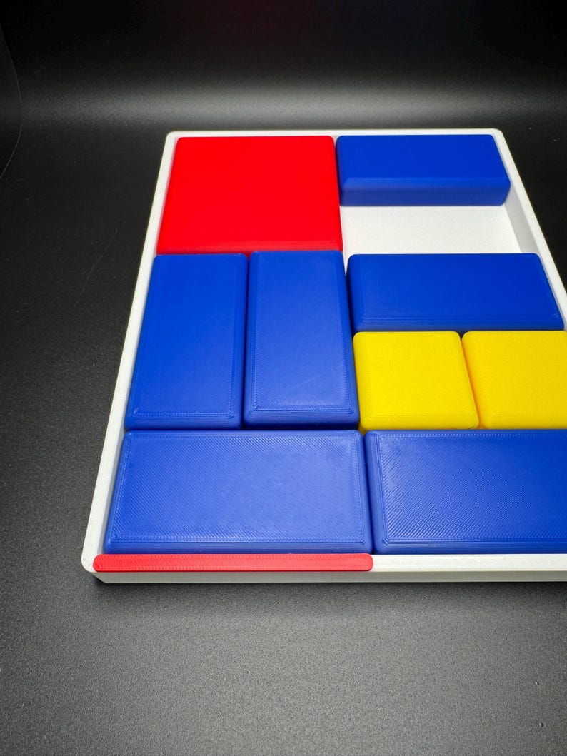 Op de afbeelding: Een witte dienblad met een rood, blauw en geel geometrisch patroon. Het dienblad is gemaakt van plastic en heeft een textuur.