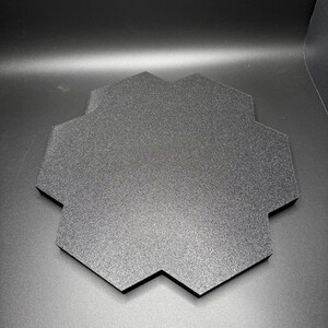 May include: A black hexagonal display stand with a textured surface.