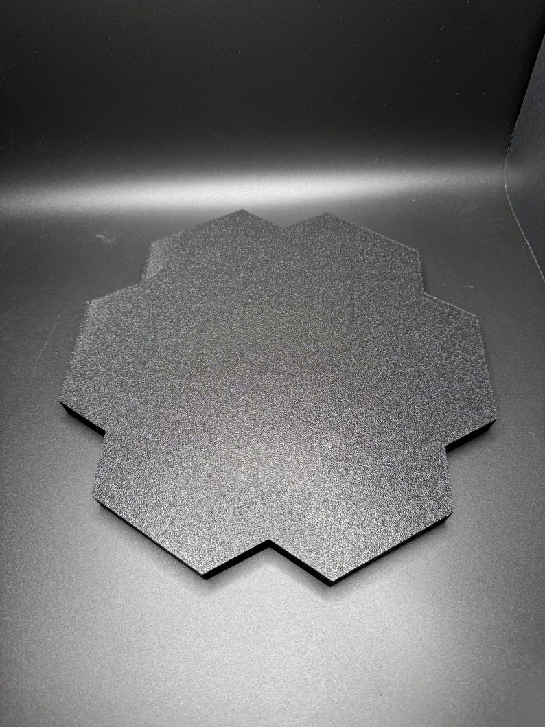 May include: A black hexagonal display stand with a textured surface.