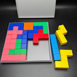 May include: A wooden puzzle with a gray base and a variety of colored blocks. The blocks are arranged in a pattern, and there are some extra blocks off to the side. The puzzle is in a partially completed state.