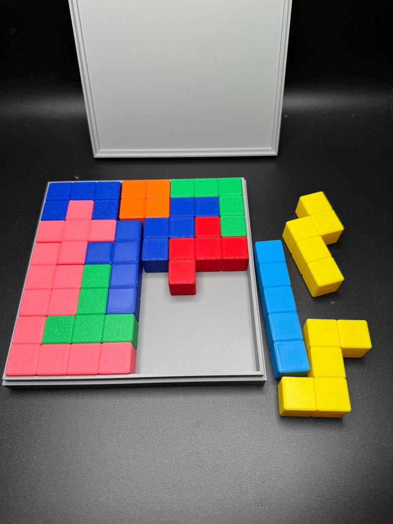 May include: A wooden puzzle with a gray base and a variety of colored blocks. The blocks are arranged in a pattern, and there are some extra blocks off to the side. The puzzle is in a partially completed state.