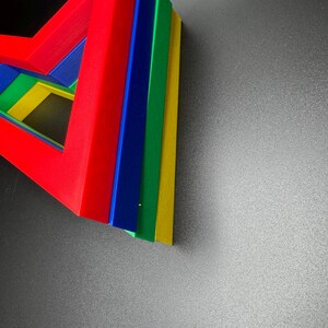 May include: A set of five colorful geometric shapes stacked on top of each other. The shapes are red, blue, green, yellow, and a lighter shade of blue. The shapes are arranged in a triangular pattern.