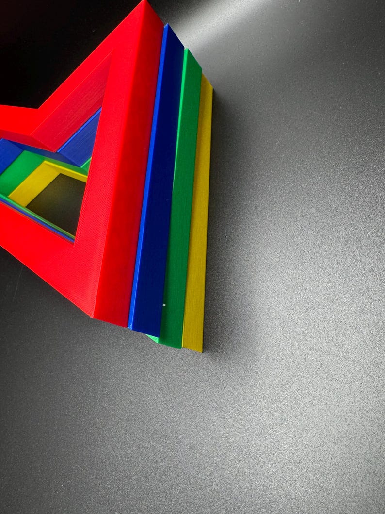 May include: A set of five colorful geometric shapes stacked on top of each other. The shapes are red, blue, green, yellow, and a lighter shade of blue. The shapes are arranged in a triangular pattern.