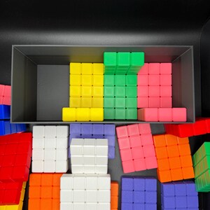 May include: A collection of colorful plastic blocks in various shapes and sizes. The blocks are arranged in a random pattern and include red, yellow, green, blue, orange, and white.