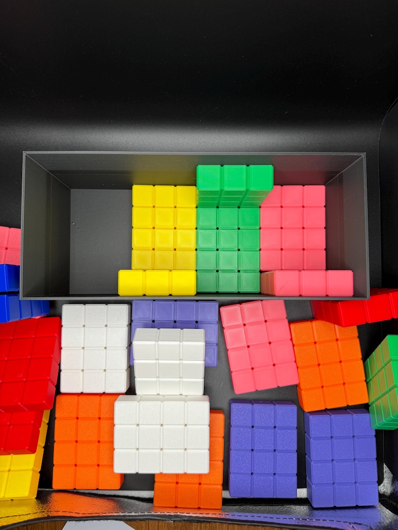 May include: A collection of colorful plastic blocks in various shapes and sizes. The blocks are arranged in a random pattern and include red, yellow, green, blue, orange, and white.