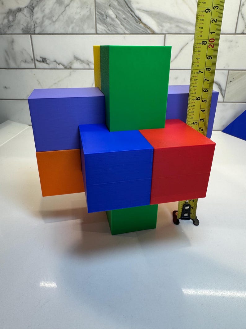 May include: A colorful wooden block puzzle with six blocks in different colors: blue, green, red, orange, yellow, and purple. The blocks are arranged in a cross shape, with the blue block in the center. The blocks are measured with a tape measure.