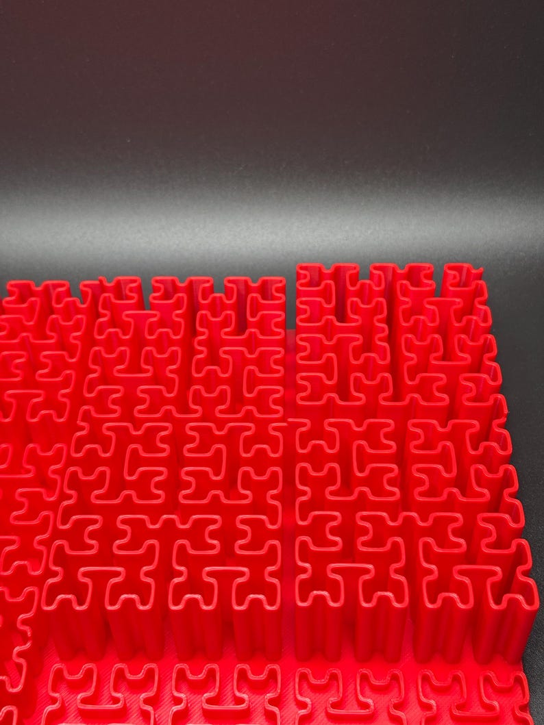 May include: A red plastic puzzle mat with interlocking pieces. The mat is made up of a grid of small squares, each with a unique shape.