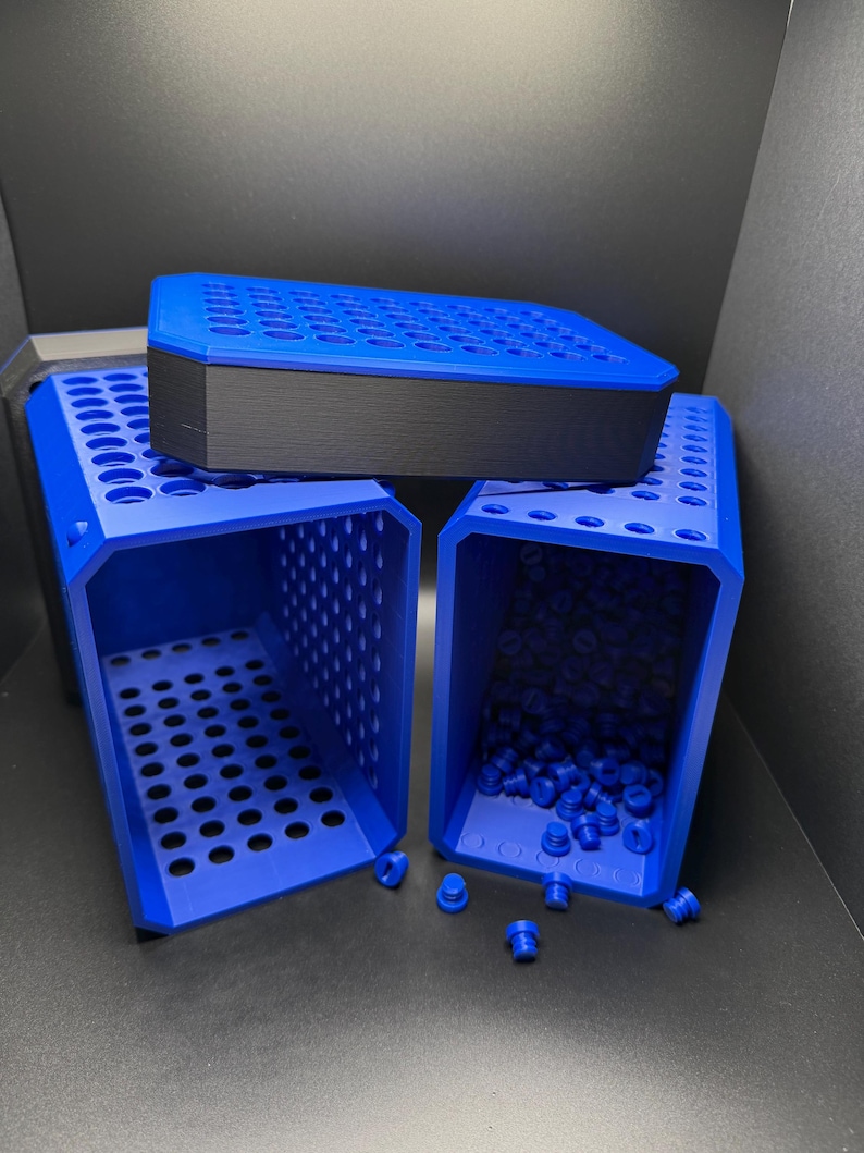 May include: Three blue plastic storage containers with a grid pattern. The containers are stacked on top of each other. The top container is closed and the bottom two containers are open. The bottom container is filled with small blue plastic caps.