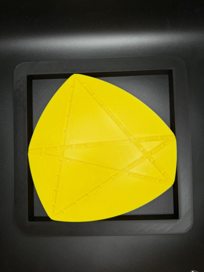 K&ouml;nnte beinhalten: Eine gelbe geometrische Form mit einer strukturierten Oberfl&auml;che, in einem schwarzen Rahmen.