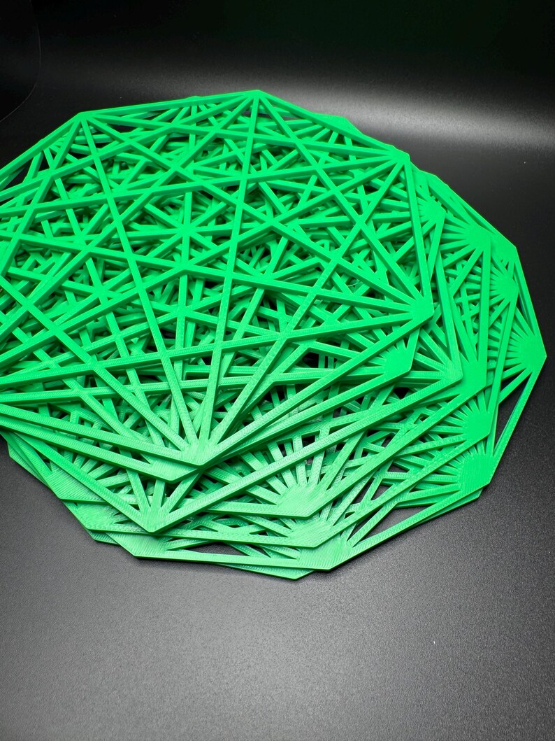 May include: A stack of green geometric, laser-cut, decorative coasters. The coasters are made of a thin, rigid material and have a delicate, intricate design.
