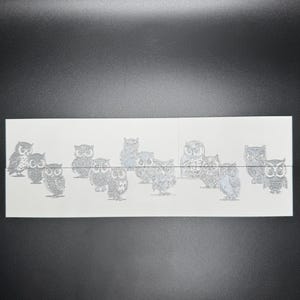 May include: A sheet of white paper with a row of 10 black and white owl illustrations. The owls are all facing forward with their wings spread out.