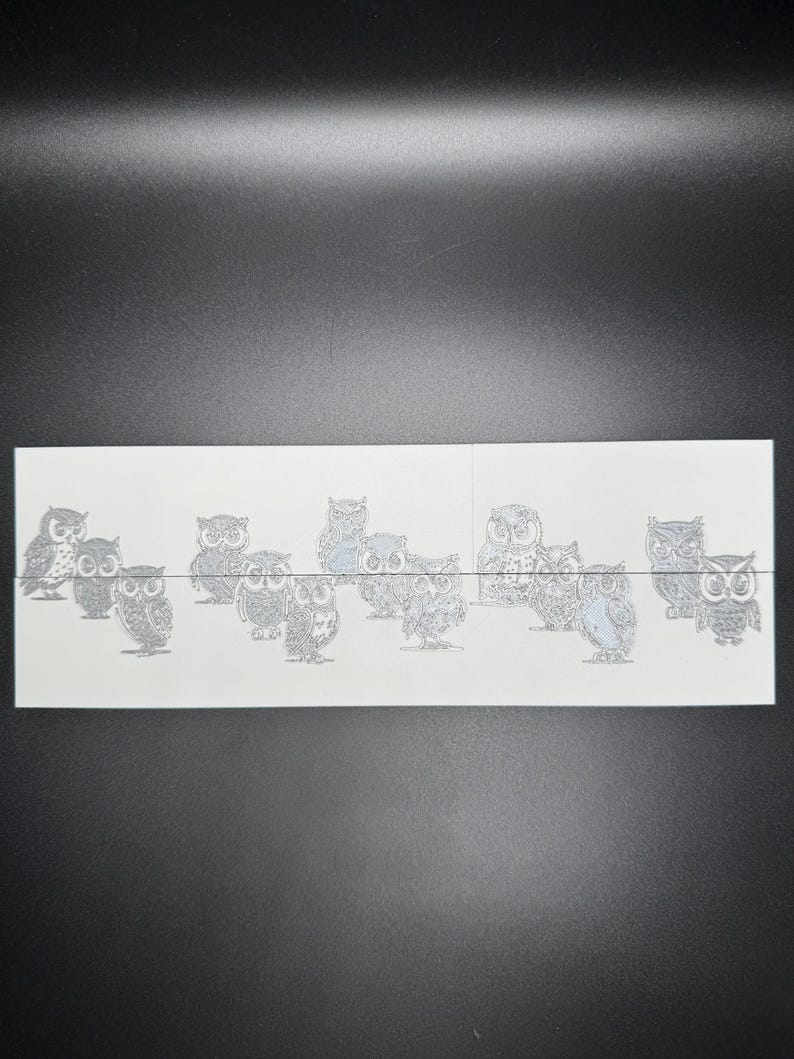 May include: A sheet of white paper with a row of 10 black and white owl illustrations. The owls are all facing forward with their wings spread out.