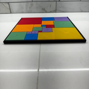 May include: A colorful puzzle with a black frame. The puzzle is made up of 14 squares, each with a different color and a number printed on it. The numbers range from 1 to 27.
