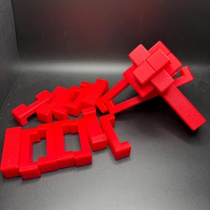 May include: A set of red plastic building blocks in various shapes and sizes. The blocks are arranged in a pile on a black surface.