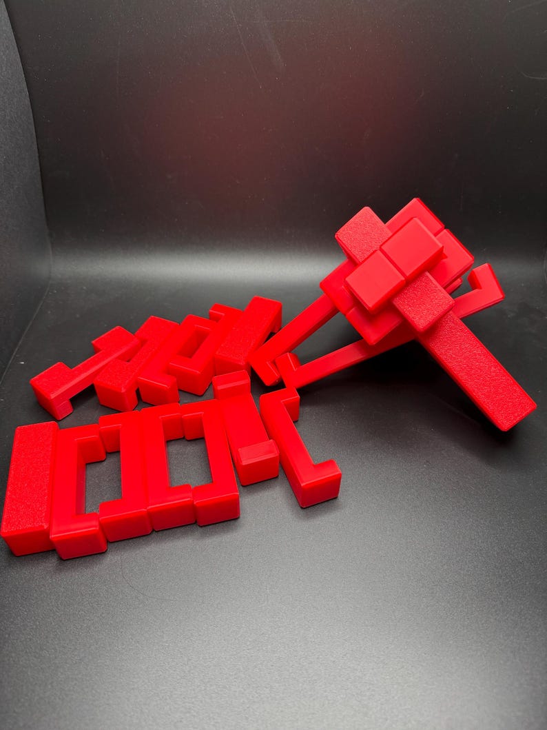 May include: A set of red plastic building blocks in various shapes and sizes. The blocks are arranged in a pile on a black surface.