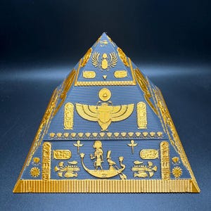 Puede incluir: Una pir&aacute;mide dorada detallada con intrincados jerogl&iacute;ficos y s&iacute;mbolos egipcios sobre una superficie azul oscuro. La pir&aacute;mide presenta un dise&ntilde;o en capas con varias figuras y patrones en relieve, mostrando el arte del antiguo Egipto.
