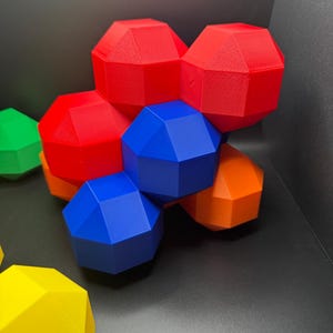 May include: A group of geometric shapes made of plastic in red, blue, orange, and green colors. The shapes are arranged in a cluster, with some overlapping.