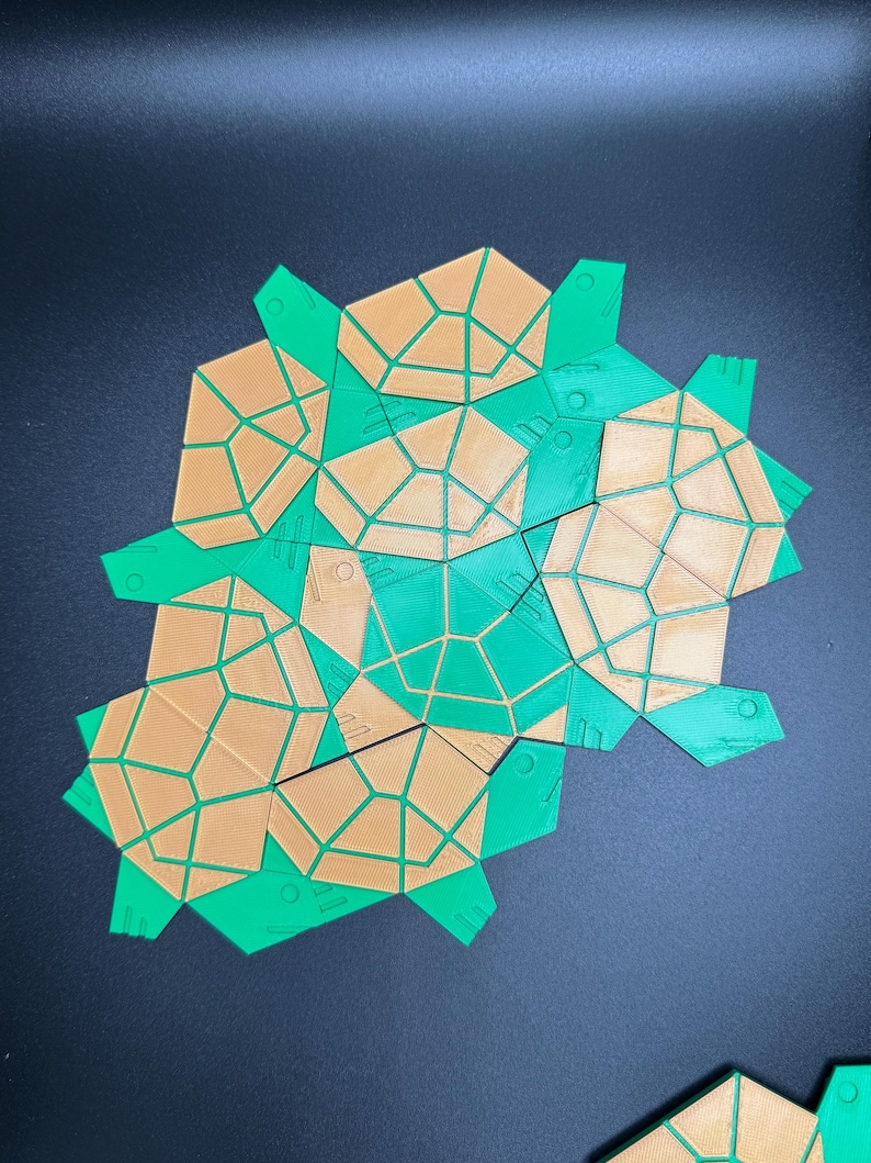 May include: A geometric puzzle made of green and brown plastic pieces. The pieces are shaped like irregular hexagons and have a honeycomb pattern.