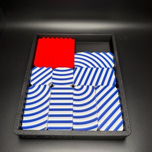 May include: A black tray with a red block and blue and white striped blocks.