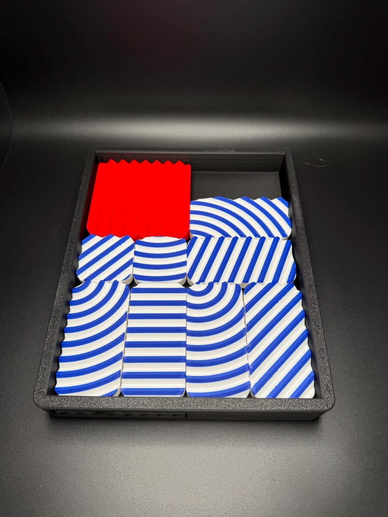 May include: A black tray with a red block and blue and white striped blocks.