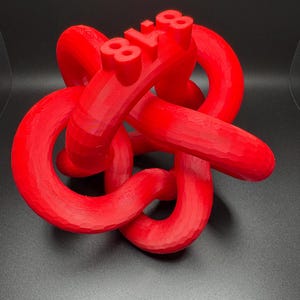 May include: A red 3D printed sculpture of a knot with the number "81.8" printed on it.