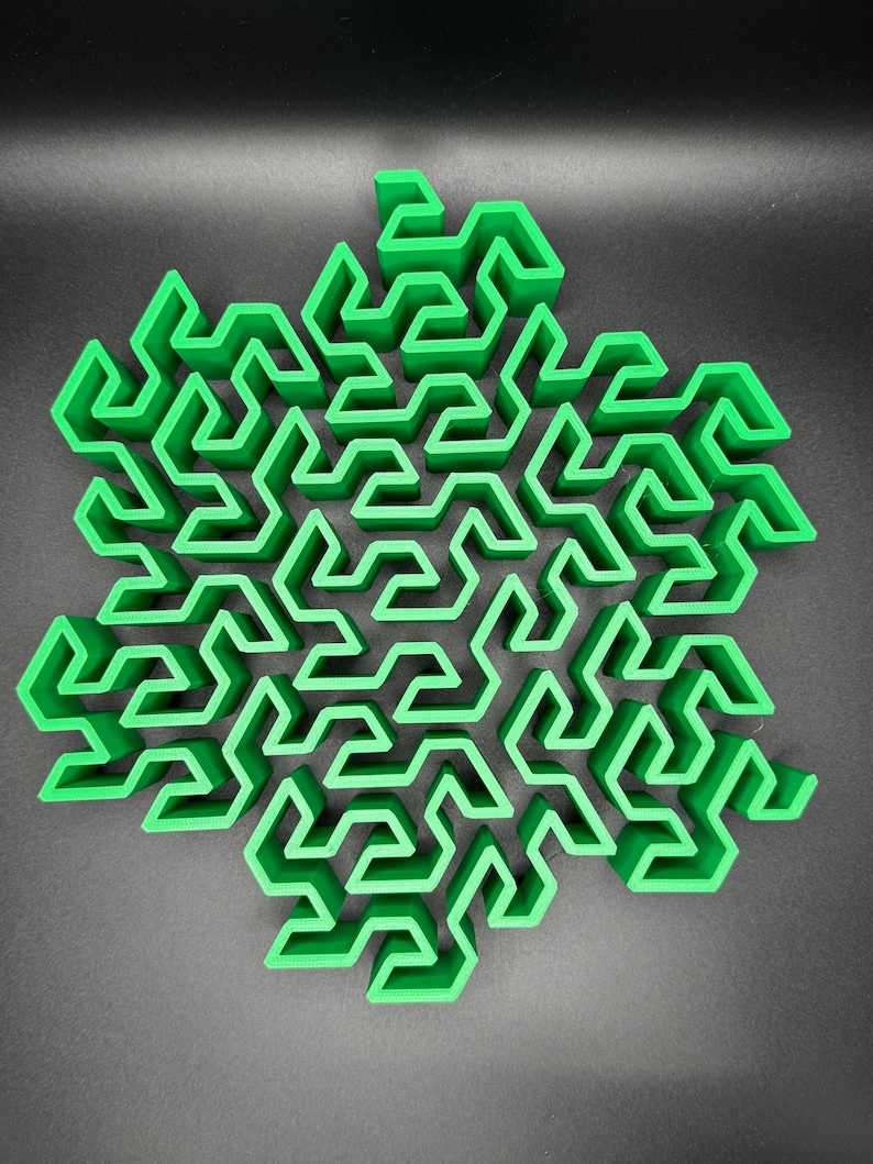 May include: A green 3D printed snowflake shaped maze with a complex design.
