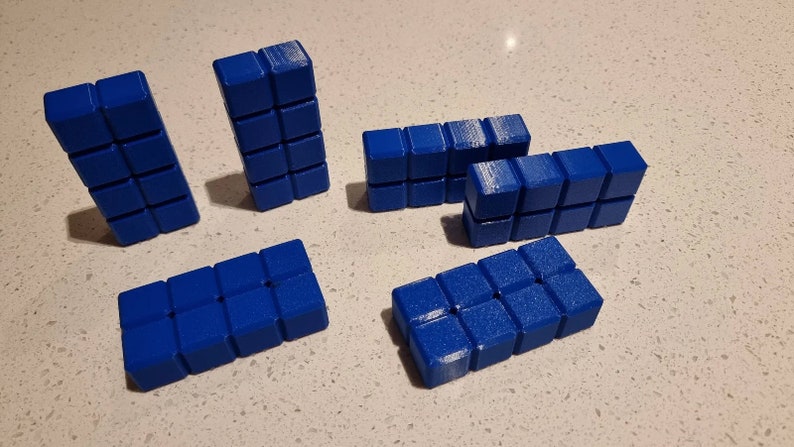 May include: Six blue building blocks made of small squares. The blocks are arranged in different configurations.
