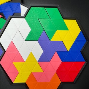 May include: A colorful geometric puzzle with triangular pieces in shades of green, yellow, blue, purple, pink, orange, red, and white. The pieces fit together to form a hexagonal shape.
