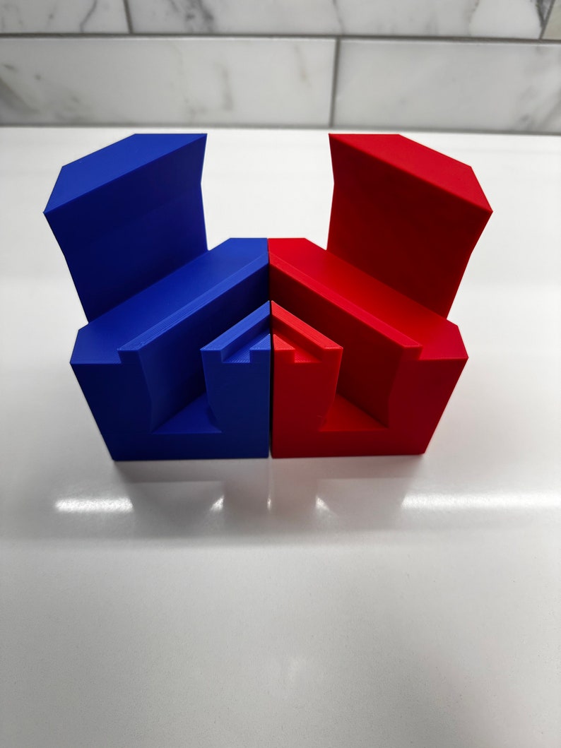 May include: Two geometric shapes, one blue and one red, are joined together. The shapes are made of a smooth, solid material and have a modern, abstract design.