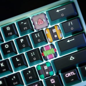 May include: A keyboard with custom keycaps featuring various cartoon characters. The keycaps are made of plastic and have a glossy finish. The keyboard is black and has a blue backlight.