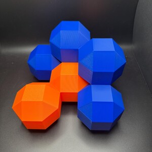 May include: A group of geometric shapes made of 3D printed plastic. The shapes are arranged in a cluster, with some overlapping. The shapes are blue and orange.