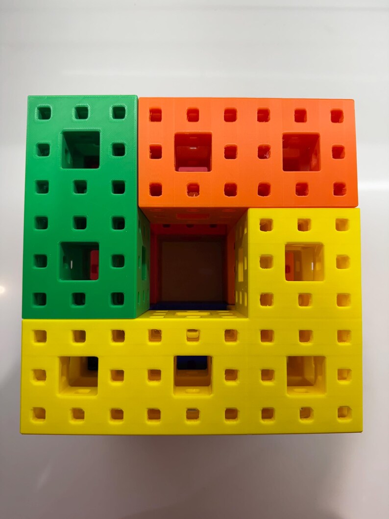 May include: A set of four colorful plastic building blocks, each with a grid of small holes. The blocks are stacked to form a square, with the top block being orange, the second block being green, the third block being yellow, and the bottom block being blue.