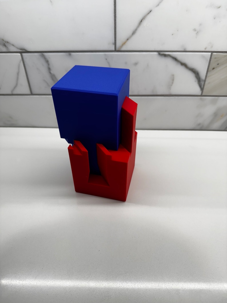 May include: A blue cube stacked on top of a red cube with an intricate interlocking design. The cubes are made of a smooth, solid material.