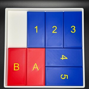 May include: A white tray with five blue and two red tiles. The blue tiles have the numbers 1, 2, 3, 4, and 5 printed in yellow. The red tiles have the letters B and A printed in yellow.