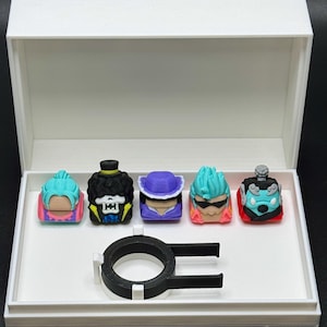 May include: A white box with a black ring and five colorful 3D printed keycaps featuring characters from the anime One Piece. The keycaps are Luffy, Brook, Sanji, Zoro, and Franky.