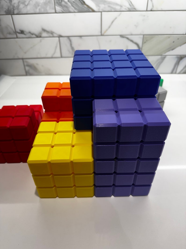 May include: A stack of colorful building blocks made of small squares. The blocks are blue, purple, yellow, orange, and red. The blocks are arranged in a staggered pattern.