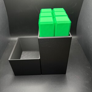 May include: A black organizer with a removable tray. The organizer has a compartment for storing small items, and the tray can be used to hold larger items. The organizer is made of plastic and has a sleek, modern design.
