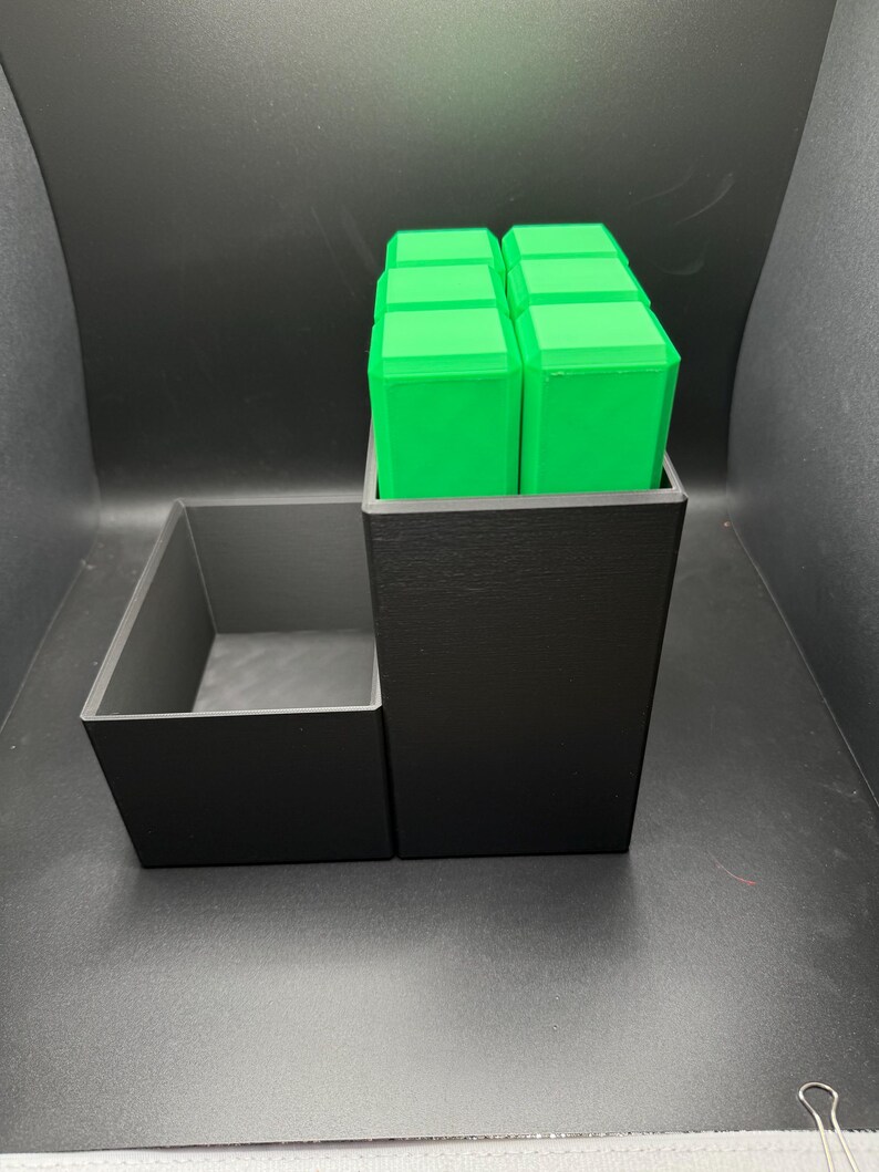May include: A black organizer with a removable tray. The organizer has a compartment for storing small items, and the tray can be used to hold larger items. The organizer is made of plastic and has a sleek, modern design.