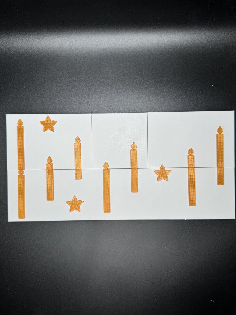 Puede incluir: Una tarjeta blanca con dise&ntilde;os de velas y estrellas naranjas. Las velas var&iacute;an en altura y est&aacute;n dispuestas verticalmente. Las estrellas tienen cinco puntas. La tarjeta est&aacute; dividida en tres secciones.