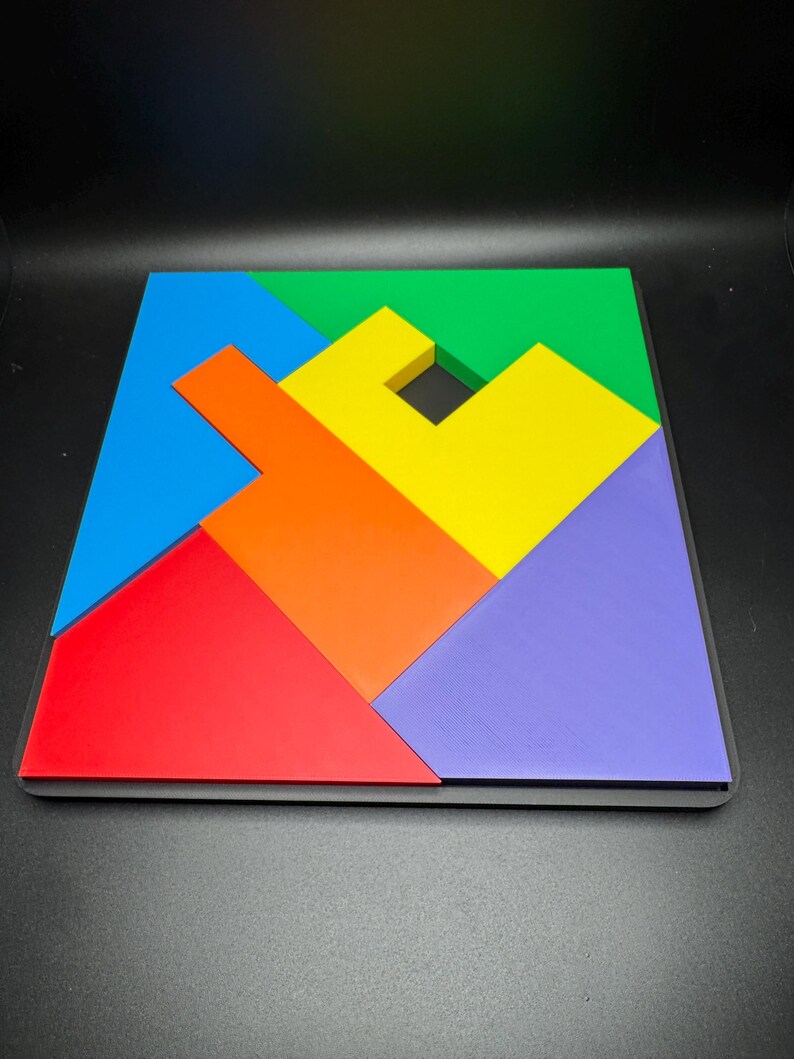 May include: A colorful wooden puzzle with six pieces, including a blue, green, yellow, orange, red, and purple piece. The pieces are arranged to form a square shape with a small hole in the center.