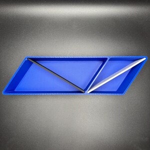 May include: A blue, triangular-shaped desktop organizer with two compartments. One compartment has a black divider and the other has a white divider.