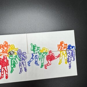 Pu&ograve; includere: Una carta bianca con un design arcobaleno di giocatori di football. I giocatori sono in varie pose, tra cui correre, calciare e lanciare la palla. La carta &egrave; divisa in due sezioni, con i giocatori sul lato sinistro della carta in un motivo arcobaleno dal rosso al viola, e i giocatori sul lato destro della carta in un motivo arcobaleno dal viola al rosso.