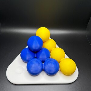 May include: A triangular puzzle game with blue and yellow balls. The balls are arranged in a pyramid shape on a white base.