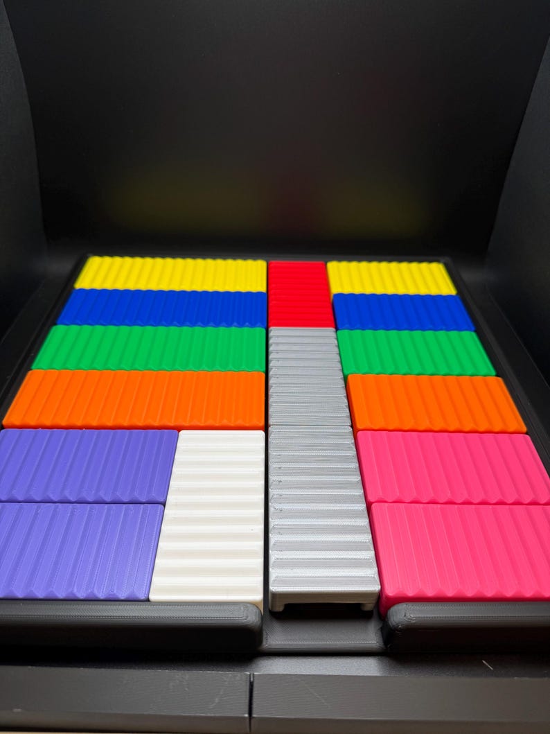 May include: A colorful puzzle game with rectangular pieces in various colors, including blue, green, orange, purple, white, gray, red, and pink. The pieces have a ridged texture and are arranged in a grid-like pattern.