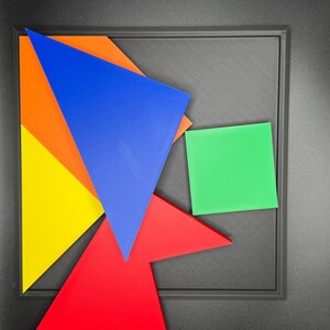 May include: A set of five colourful geometric shapes, including a blue triangle, a red triangle, a yellow triangle, an orange triangle, and a green square, arranged on a black surface.