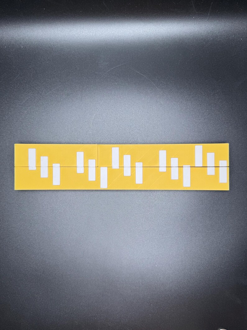May include: A yellow ruler with white markings. The ruler is divided into sections with different lengths of white markings.