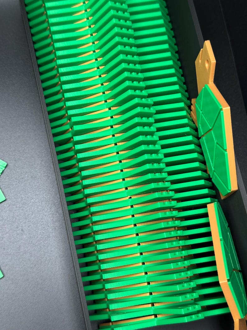 May include: A close-up of a green and gold plastic toy building block set. The blocks are arranged in a zig-zag pattern and are stacked on top of each other.