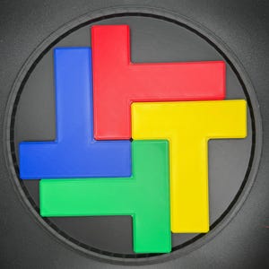 Op de afbeelding: Een ronde puzzel met vier T-vormige stukken. De stukken zijn rood, blauw, groen en geel.