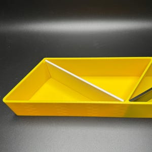May include: A yellow plastic tray with three compartments. The tray has a textured surface and is divided into three sections by white plastic dividers.