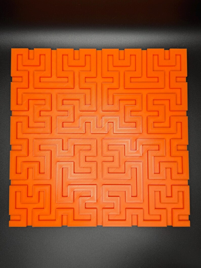 Op de afbeelding: Een oranje plastic doolhof met een complex patroon van in elkaar grijpende paden. De doolhof is ontworpen om uitdagend en leuk te zijn om op te lossen.